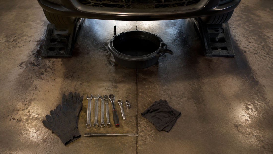 Garage floor with a car on ramps, an oil pan underneath, and black heavy duty nitrile gloves nearby