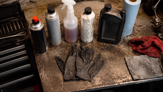 Garage workbench with black heavy duty nitrile gloves and unlabeled automotive fluid bottles